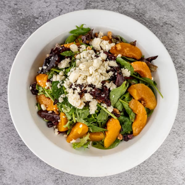 A vibrant Tres Palms salad with mixed greens, butternut squash, dried cranberries, and feta cheese.