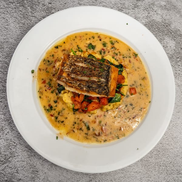 Tres Palms' pan-seared fish with crispy skin, served on polenta with spinach, tomatoes, and creamy sauce.