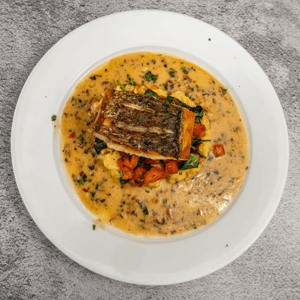 Tres Palms' pan-seared fish with crispy skin, polenta, spinach, and tomatoes in a creamy sauce.