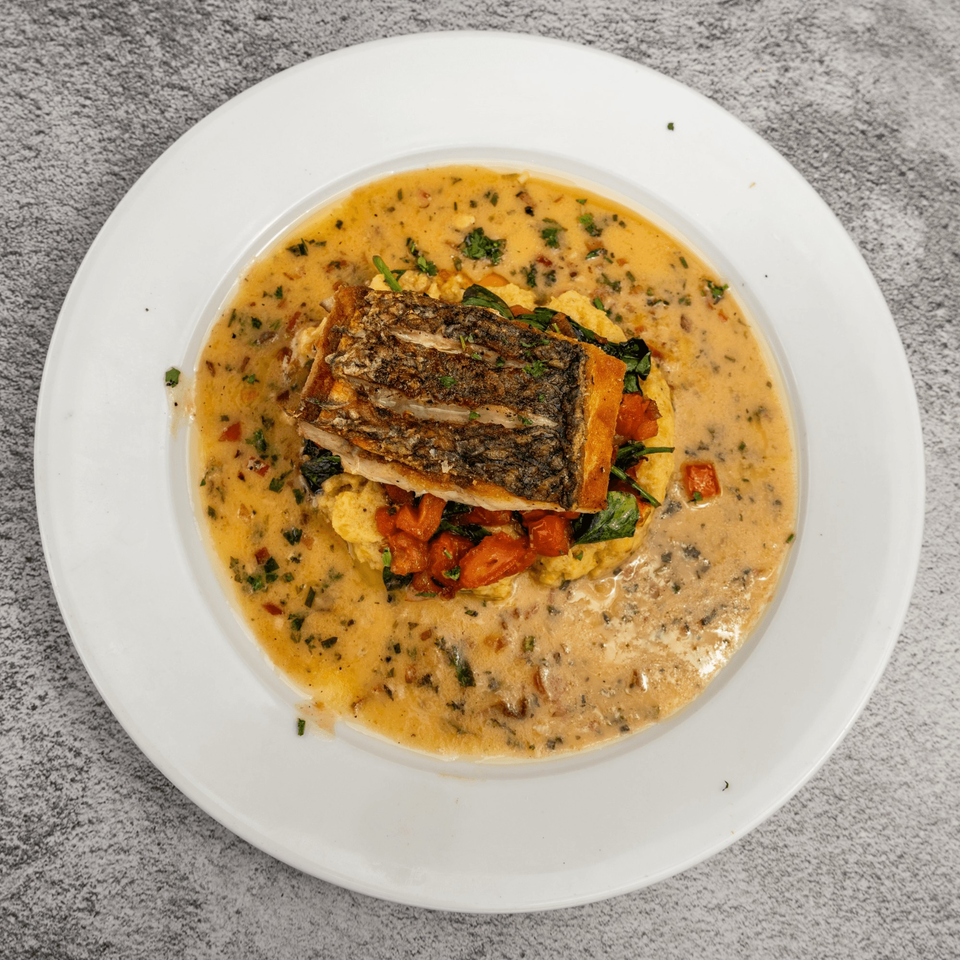 Tres Palms' pan-seared fish with crispy skin, polenta, spinach, and tomatoes in a creamy sauce.
